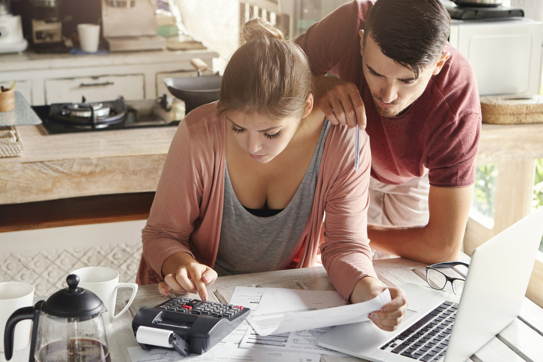 Family calculating water filter cost savings with calculator next to under-sink filtration system in modern kitchen