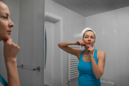 Woman examining dry irritated skin after hard water shower highlighting need for shower head water filter