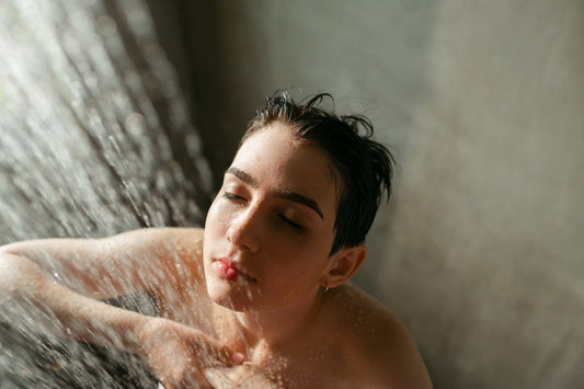 Person experiencing weak water flow from standard shower head before installing filtered shower head for low pressure