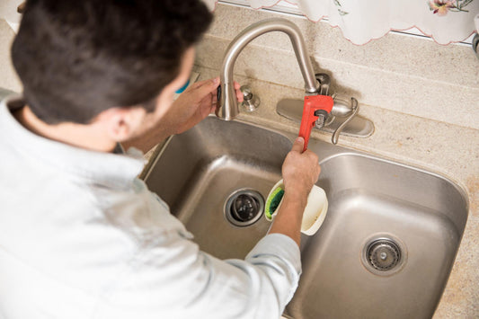 DIY homeowner installing under-sink water filtration system in modern kitchen