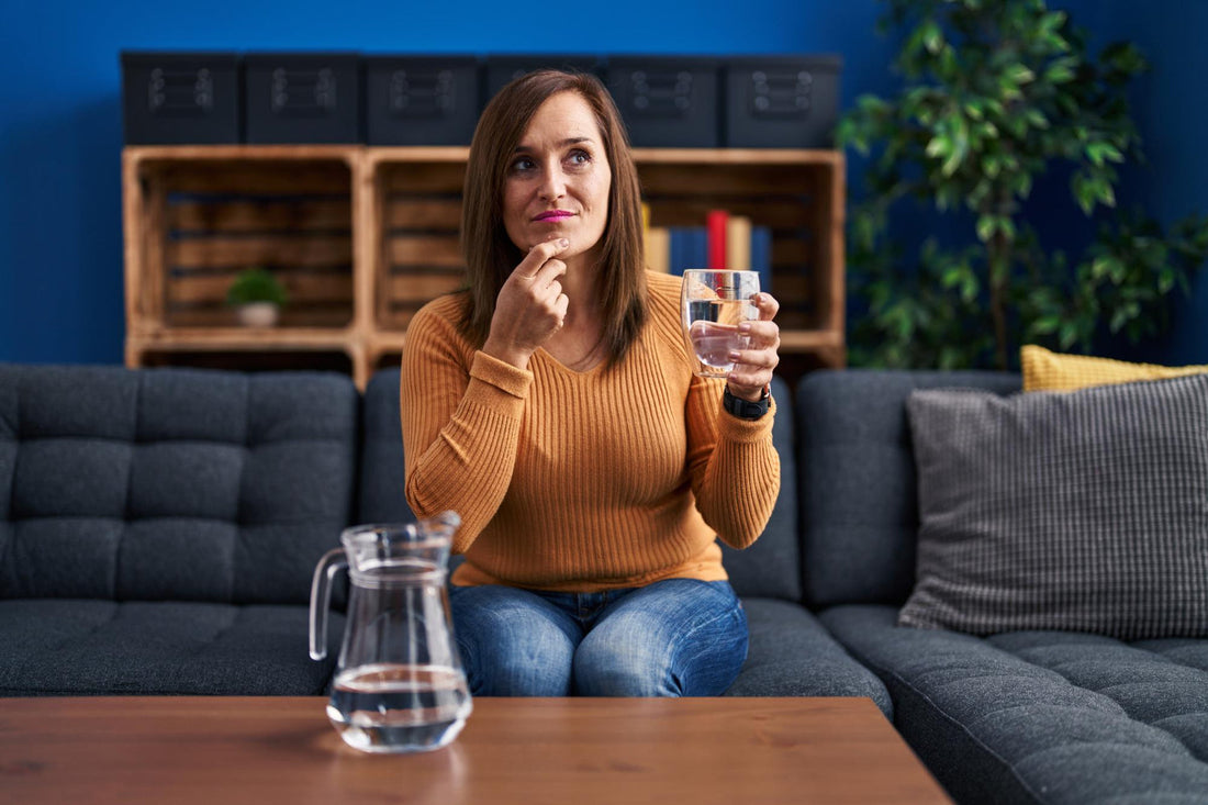 Woman drinking clear filtered water from glass testing water quality at home