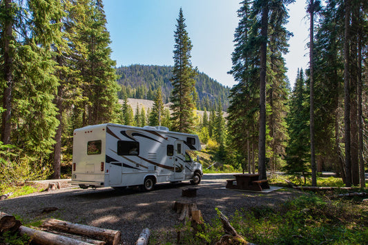 Modern motorhome parked at mountain forest campground where RV water filter systems ensure clean drinking water during outdoor adventures