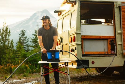 RV traveler installing portable water filter system at scenic campground for safe drinking water