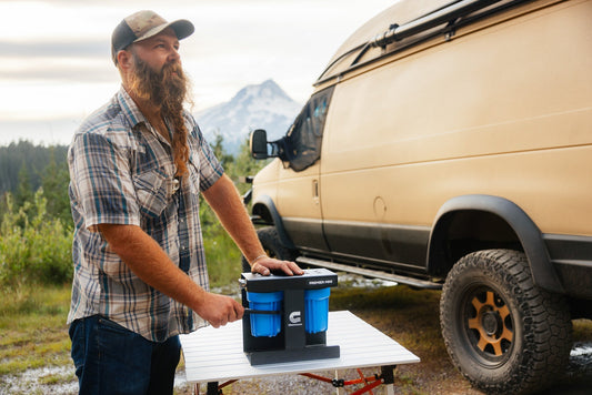 RV traveler replacing water filter housing at scenic mountain campground with portable tools and clean water supply