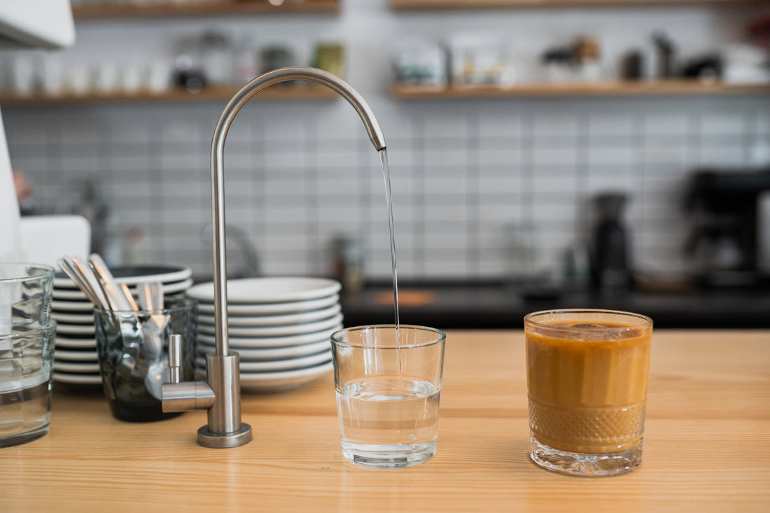 Modern kitchen faucet with crystal clear filtered water pouring into glass showcasing home water filtration benefits