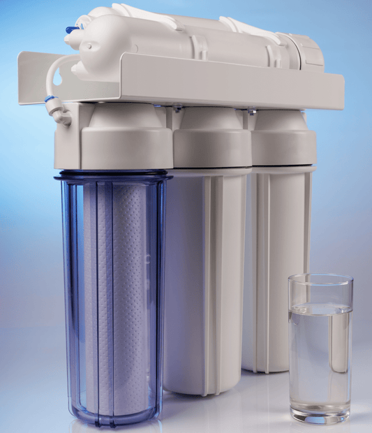Close up of a water filter system next to a glass of clear water.