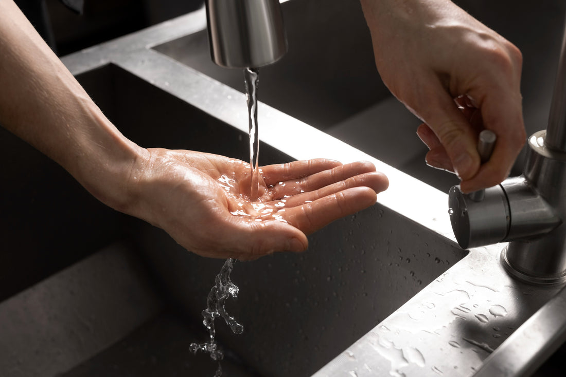 Human hands under gentle stream from tap