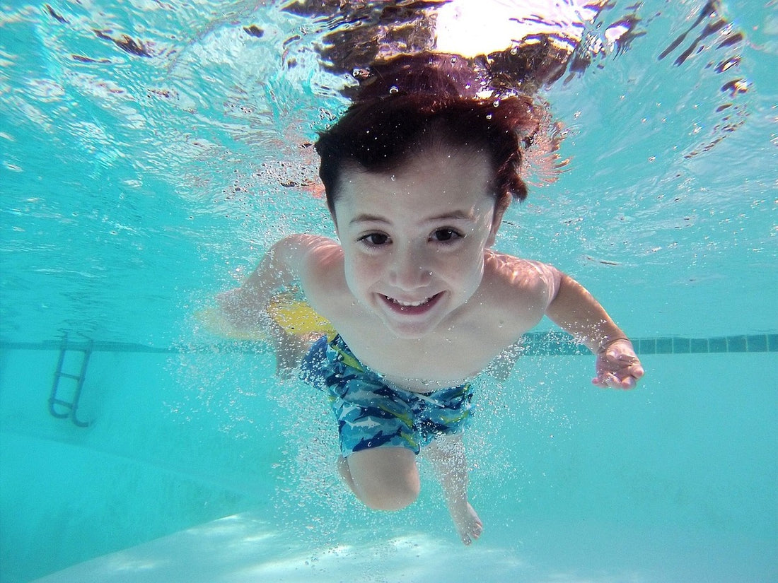 Kid swimming in a pool with crystal clear water.