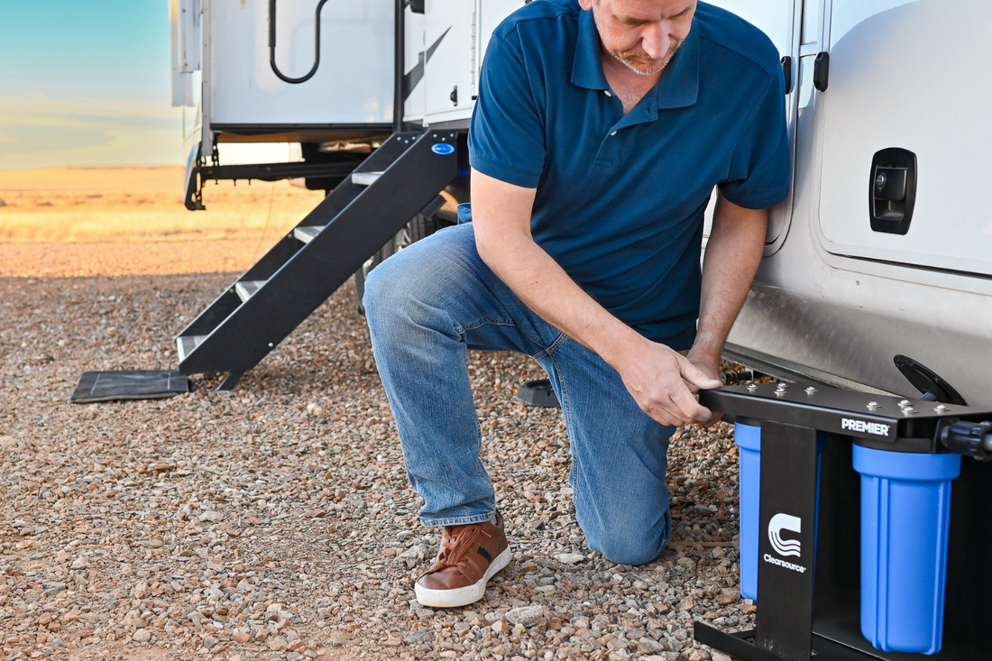 RV owner installing portable water filtration system at campground hookup for clean drinking water