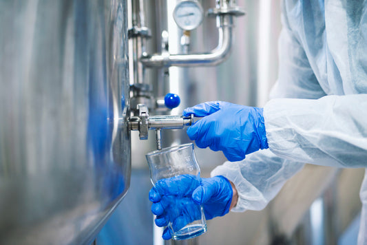 close-up-view-hands-protective-gloves-opening-tap-valve-filling-glass-with-samples-from-industrial-machine-reservoir