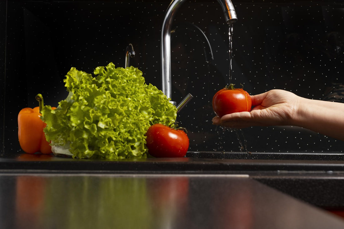Clean water pouring from kitchen faucet washing vegetables