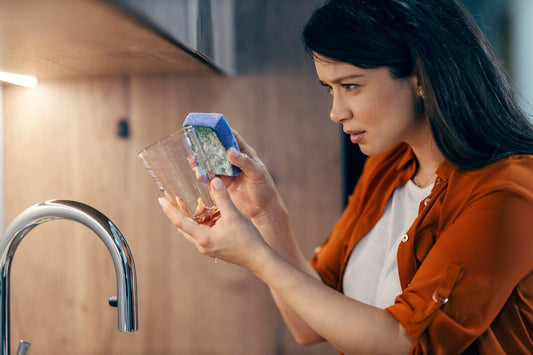 Woman examining glass of clear tap water questioning if unfiltered water is causing health problems