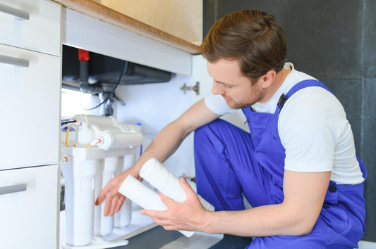 Professional technician installing new water filter cartridge in under-sink system for extended lifespan maintenance